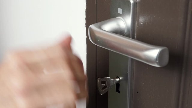 Hand inserting the key into keyhole of old wooden door and closing locking up, pushing the handle. Home safety and security. 4K ProRes HQ codec