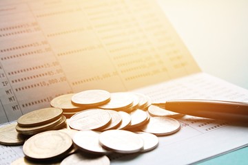 Business, finance, savings or loan concept : Pen and coins on saving account passbook or financial...
