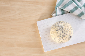 Raw dough with poppy seeds on wooden board
