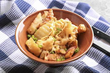 Bowl with tasty baked potato, bacon and cheese on table