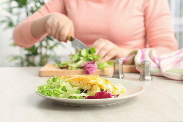 Obraz na płótnie Canvas Woman cutting mixed salad for tasty casserole in kitchen