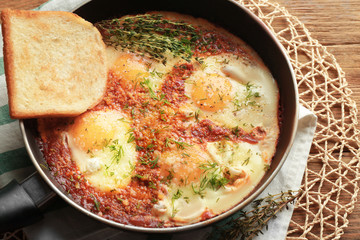 Frying pan with eggs in purgatory on table