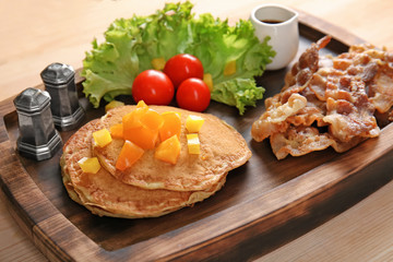 Tasty breakfast with pancakes and bacon on wooden board