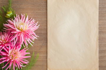 Greeting card with pink aster flowers on the wooden table. Empty place for a text.