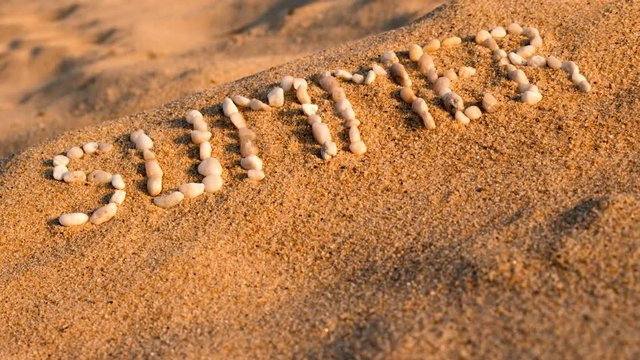 Summer. Writing the word by small pebbles on sandy beach. Stop motion animation