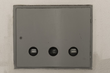 Closed electricity control box on white wall.