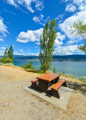 Picnic table and benches on shore of Okanagan lake