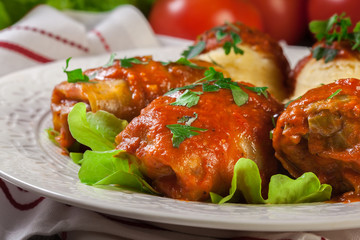 Stuffed cabbage with meat and rice served with boiled potatoes and tomato sauce