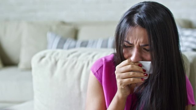 Zoom out of sad Latin woman with handkerchief crying hysterically and shaking her head during appointment with unrecognizable psychotherapist