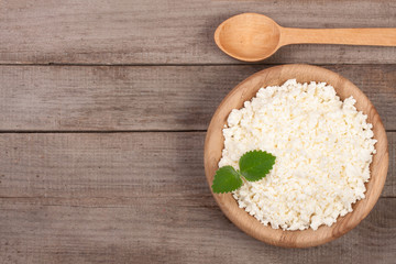 Cottage cheese in a wooden bowl on old wooden background with copy space for your text. Top view