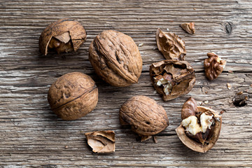 Walnuts on a wooden aged rustic background. Broken, crushed walnuts