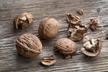 Walnuts on a wooden aged rustic background. Broken, crushed walnuts