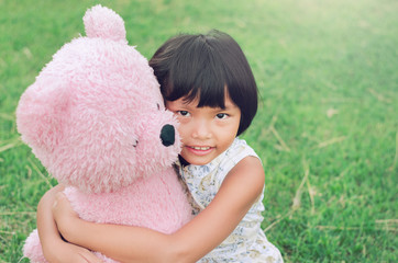 little girl is good friend with  teddy bear and sitting at the playground at the park