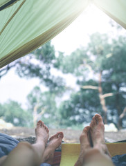 view from inside a tent at the forest and legs of two people emerge from tent. travel and hiking concept. Tourist tent inside with people