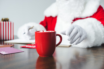 Obraz na płótnie Canvas santa drinking hot chocolate with marshmallows