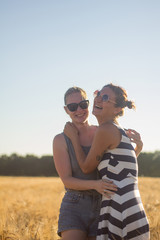 Lovely lesbian couple together, holding hands and having good time in summer wheat fields