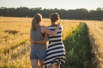 Lovely lesbian couple together, holding hands and having good time in summer wheat fields