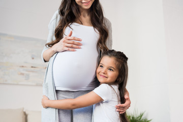 Girl hugging pregnant mother