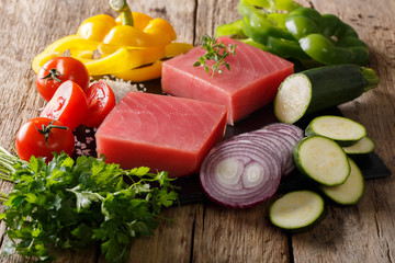 Raw fillet of tuna with pepper, onions, tomatoes, zucchini and greens close-up. horizontal
