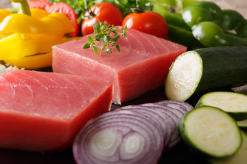 Raw steaks from tuna and fresh vegetables, spices macro. horizontal background