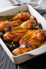 Chicken legs baked with red onions and greens in honey-soy sauce close-up. vertical