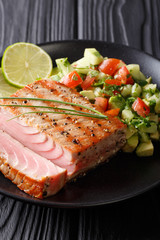 Freshly cooked grilled tuna steak with avocado cucumber salsa close-up. vertical