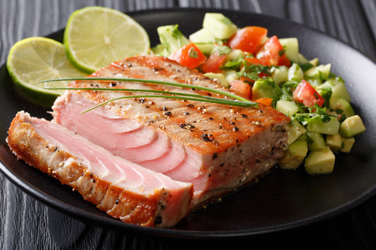 Barbecue tuna steak with lime and avocado cucumber salsa closeup. horizontal