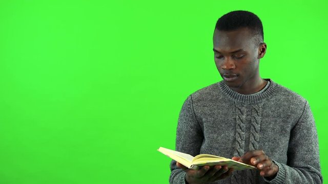 A young black man reads a book - green screen studio