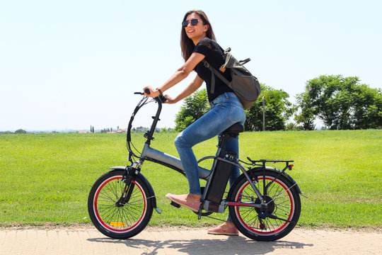 A smiling woman with electric bicycle  in the park