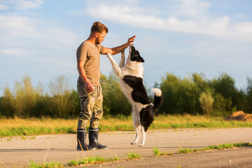 man holds a treat and lets a border collie jumping