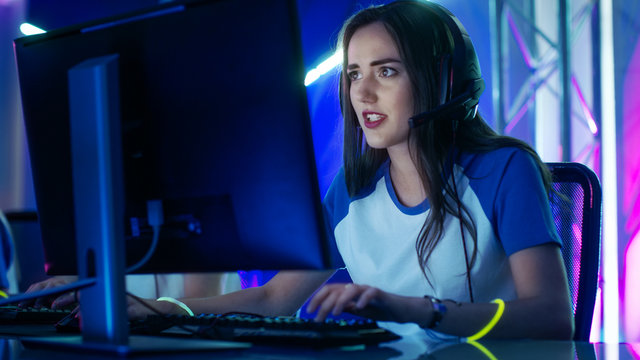 Beautiful Professional Gamer Girl and Her Team Participate in eSport Cyber Games Tournament. She Has Her Headphones and Colorful Band on.