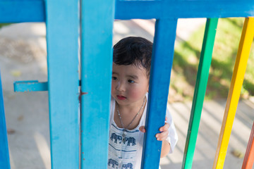 Fototapeta premium Sad Asian kid behind the grid trying to escape. shallow DOF