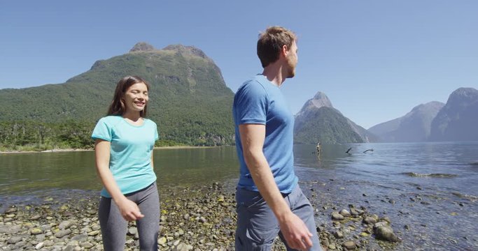 People hiking in New Zealand in Milford Sound by Mitre Peak in Fiordland. Couple on New Zealand travel visiting famous tourist destination and attraction on south island, New Zealand.