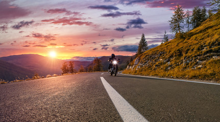 Motorcycle driver riding in Alpine highway. Outdoor photography, mountain landscape.