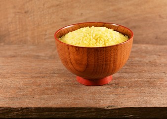 Rice cooked with turmeric in a wooden bowl on an old wooden floor.
