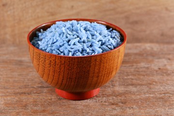 Rice cooked with water pea flower in a wooden bowl on an old wooden floor.