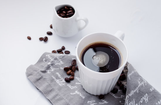 Kaffeetasse mit Bohnen auf einem weißen Tisch