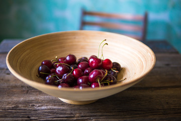 Cherry in a wooden plate in rustic style