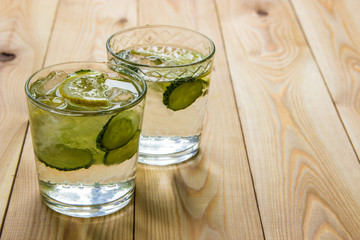Detox water with cucumber and lemon on wooden table. Cucumber lemonade