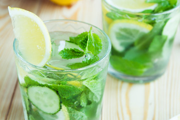 Detox water, fresh organic lemonade with ice, cucumber, lemon and mint on wooden background