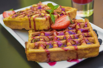 Belgium waffle topped with syrup and freshly chopped strawberries