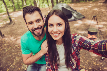 Fototapeta na wymiar Close up shot of two young cheerful lovers in the summer nice wood, embracing, posing for a selfie shot, that beautiful brunette lady is taking