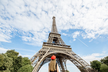 View on the Eiffel tower with woman in red cap looking up in Paris