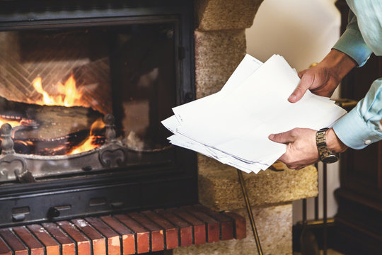Sheets of paper in hands of man and fireplace