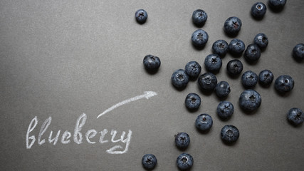 Top view of blueberries on chalkboard with text. Macro. Berries on table.