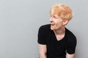 Man standing over grey wall near copyspace laughing.