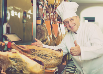 Positive mature man showing iberian jamon