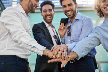 Four businessmen holding hands together laughing