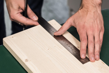 Close Up view of person-man hand holding measuring ruler tool a piece of wood for cutting