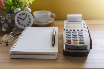 Credit Card Terminal or EDC on cashier wooden table in the store with calculator, clock,credit cards and laptop on wooden / technology and market concept